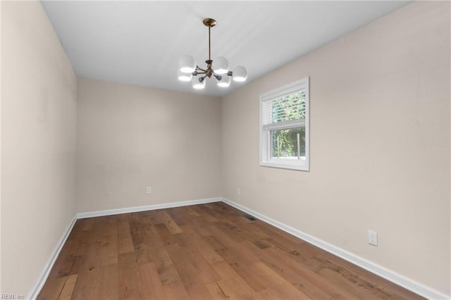 unfurnished room featuring hardwood / wood-style floors and a chandelier