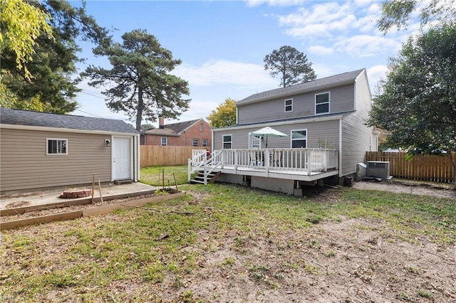 back of property with a lawn, a deck, and central AC