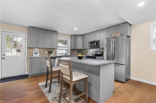 kitchen featuring a kitchen bar, light wood-type flooring, stainless steel appliances, sink, and a kitchen island