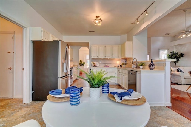 kitchen with white cabinets, decorative backsplash, ceiling fan, kitchen peninsula, and stainless steel appliances