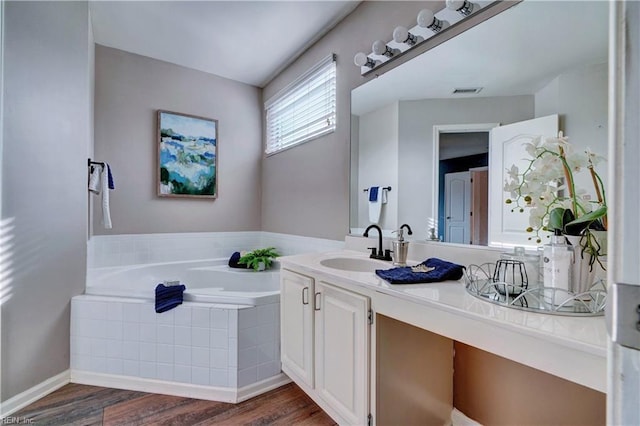 bathroom featuring tiled tub, vanity, and wood-type flooring