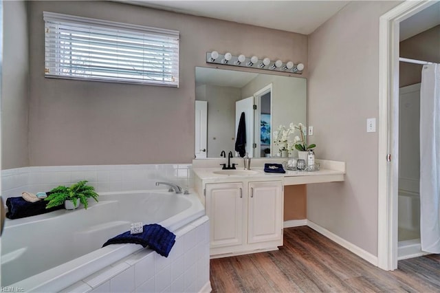 bathroom with vanity, a relaxing tiled tub, and hardwood / wood-style flooring