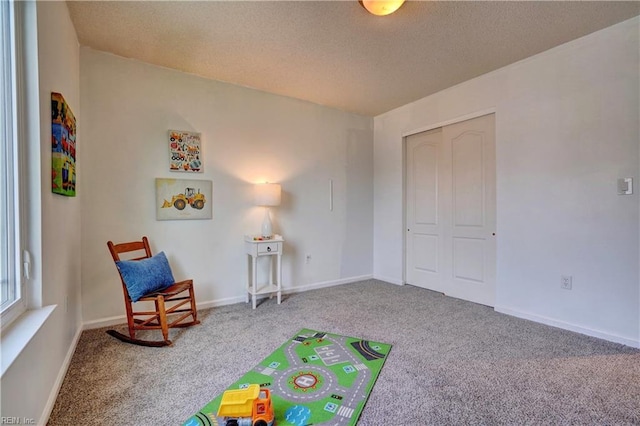 recreation room with carpet flooring and a textured ceiling