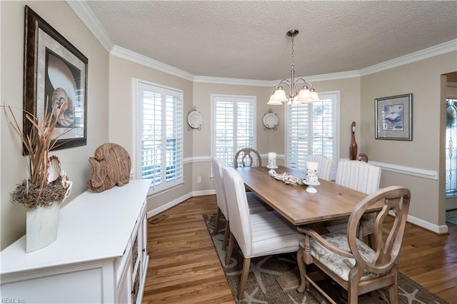 dining space featuring a chandelier, a textured ceiling, dark hardwood / wood-style flooring, and ornamental molding