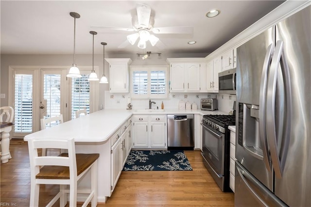 kitchen with white cabinetry, sink, pendant lighting, and appliances with stainless steel finishes