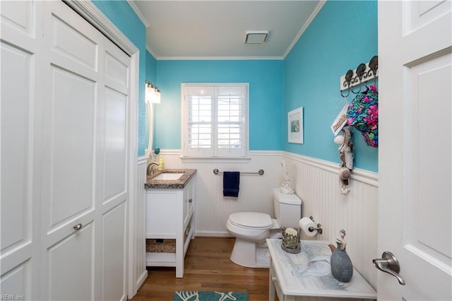 bathroom with crown molding, hardwood / wood-style floors, vanity, and toilet