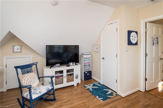 sitting room featuring wood-type flooring and vaulted ceiling