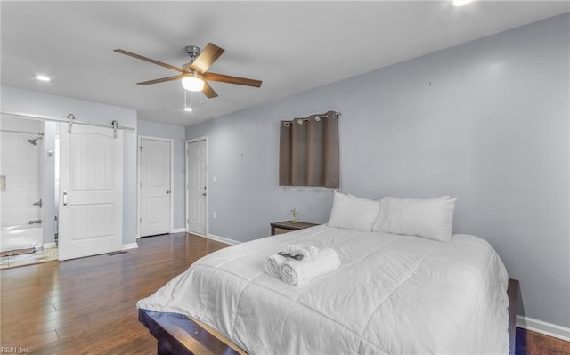 bedroom featuring connected bathroom, a barn door, ceiling fan, and dark wood-type flooring