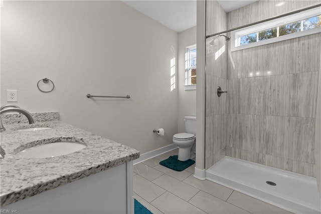 bathroom with tiled shower, tile patterned flooring, vanity, and toilet