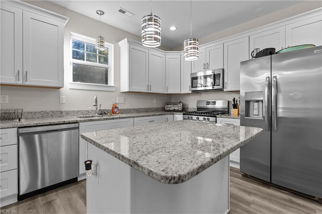 kitchen featuring a center island, hanging light fixtures, sink, appliances with stainless steel finishes, and white cabinetry