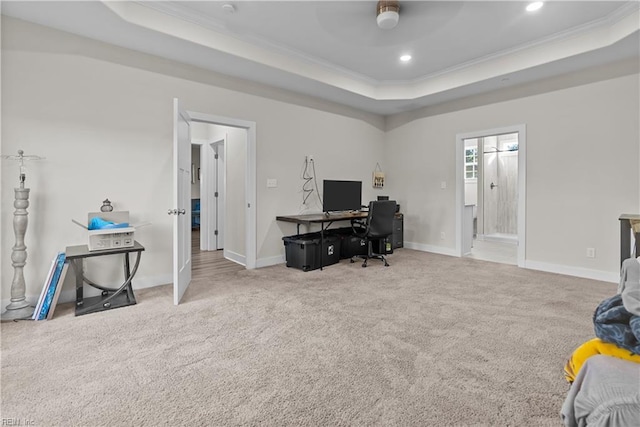 carpeted home office featuring a tray ceiling, ceiling fan, and ornamental molding