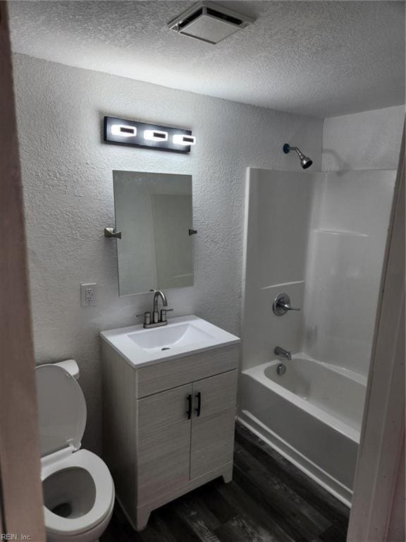 full bathroom featuring vanity, shower / tub combination, toilet, a textured ceiling, and wood-type flooring