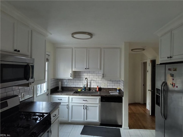 kitchen with sink, light tile patterned floors, tasteful backsplash, white cabinets, and appliances with stainless steel finishes