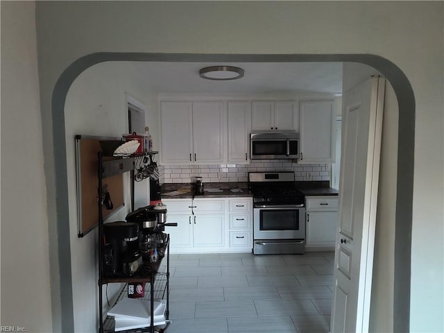 kitchen with backsplash, white cabinetry, and stainless steel appliances