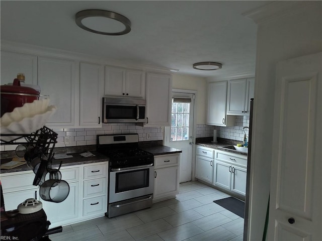 kitchen with white cabinets, appliances with stainless steel finishes, backsplash, and sink