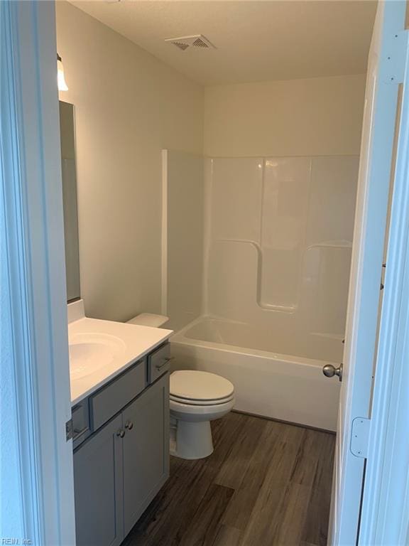 full bathroom featuring toilet, vanity,  shower combination, and hardwood / wood-style flooring