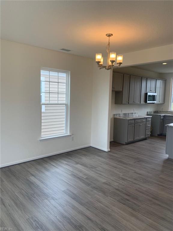 kitchen with pendant lighting, dark hardwood / wood-style flooring, gray cabinetry, and a notable chandelier