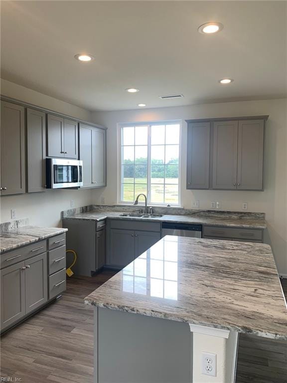 kitchen with gray cabinets, a center island, sink, and appliances with stainless steel finishes