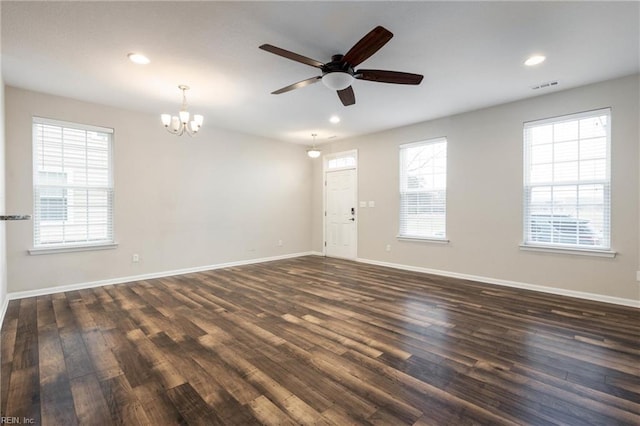 empty room with ceiling fan with notable chandelier and dark wood-type flooring