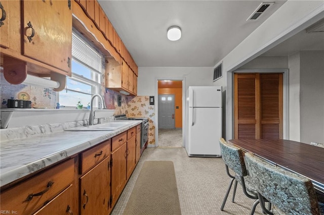 kitchen with decorative backsplash, sink, stainless steel range with electric stovetop, and white refrigerator