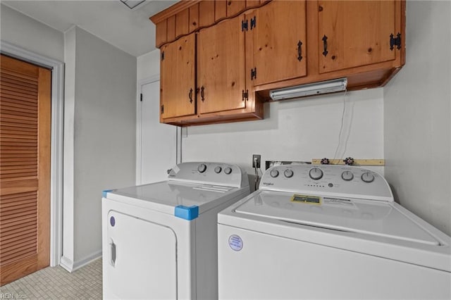 clothes washing area with separate washer and dryer and cabinets