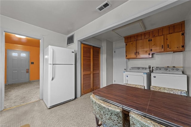 kitchen featuring washer and dryer, light carpet, and white fridge