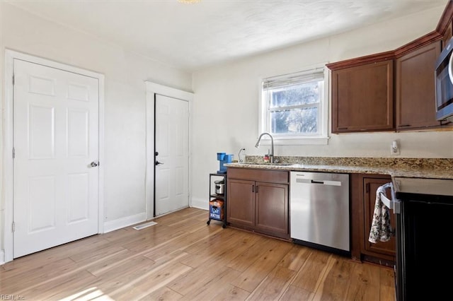 kitchen featuring light stone countertops, appliances with stainless steel finishes, light hardwood / wood-style floors, and sink