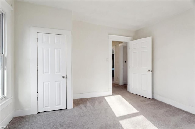 unfurnished bedroom with light colored carpet and a closet