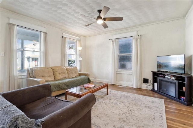 living room featuring hardwood / wood-style floors, ceiling fan, and ornamental molding