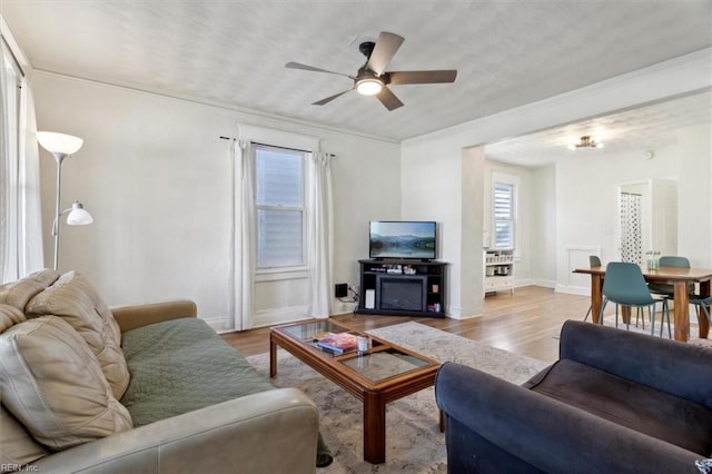 living room with light hardwood / wood-style flooring, ceiling fan, and crown molding