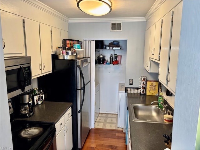 kitchen featuring sink, washing machine and clothes dryer, black range with electric cooktop, ornamental molding, and white cabinets