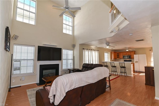 living room with a high ceiling, light hardwood / wood-style floors, and plenty of natural light