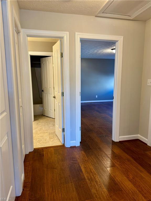 corridor featuring a textured ceiling and dark hardwood / wood-style flooring