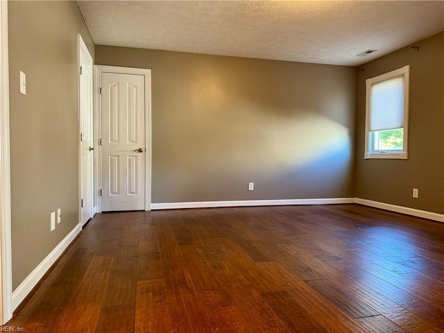 spare room with dark wood-type flooring and a textured ceiling