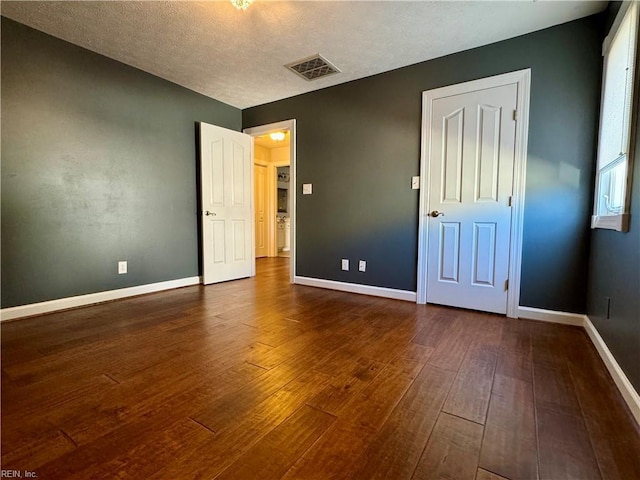 unfurnished bedroom with a textured ceiling and dark hardwood / wood-style floors