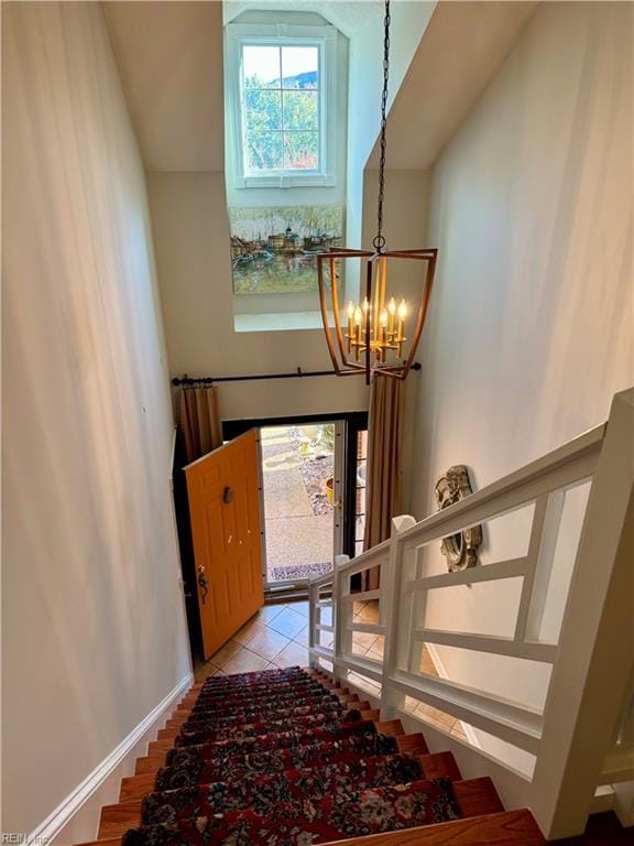 staircase featuring tile patterned flooring, a high ceiling, and an inviting chandelier