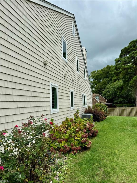 view of side of home with central AC unit and a yard