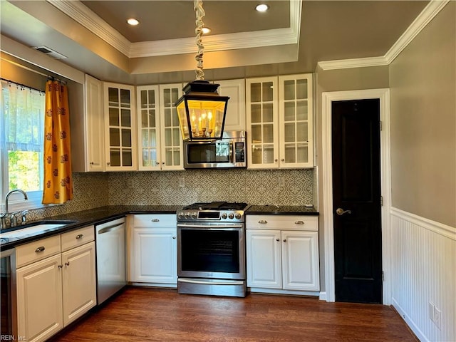 kitchen with backsplash, white cabinets, sink, hanging light fixtures, and stainless steel appliances