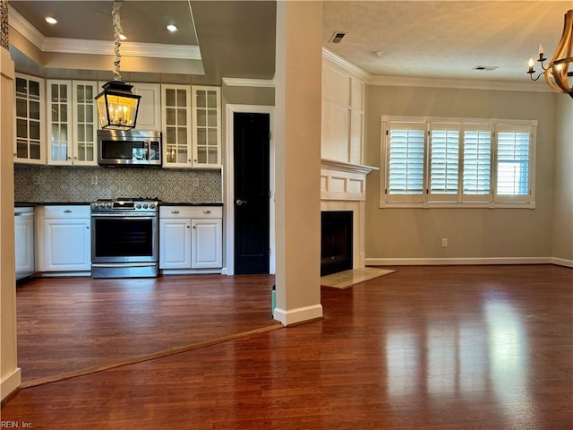 kitchen with hanging light fixtures, dark hardwood / wood-style floors, backsplash, crown molding, and appliances with stainless steel finishes