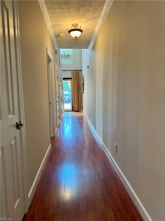 hallway featuring a textured ceiling, wood-type flooring, and crown molding