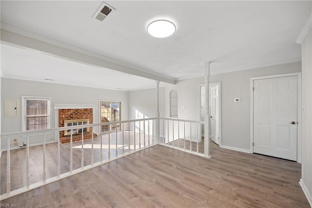 empty room featuring crown molding, hardwood / wood-style floors, and a brick fireplace