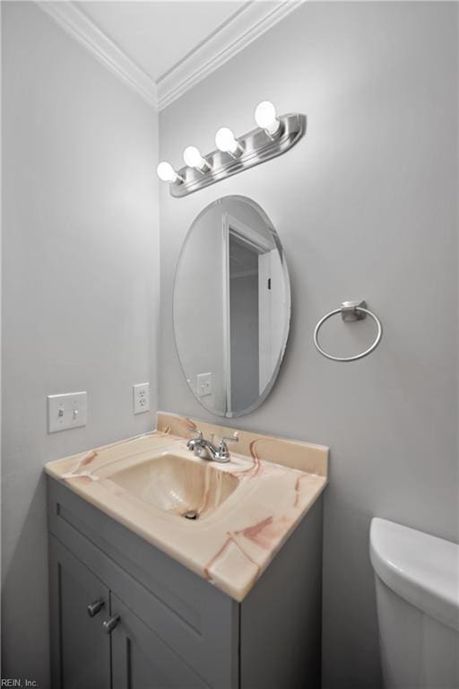 bathroom featuring toilet, vanity, and ornamental molding