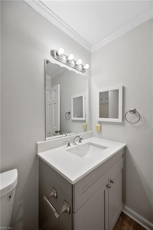 bathroom with toilet, vanity, and ornamental molding