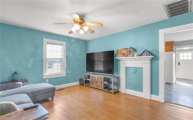 living room featuring a fireplace, hardwood / wood-style floors, and ceiling fan