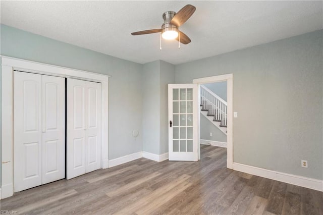 unfurnished bedroom featuring ceiling fan, a closet, and hardwood / wood-style flooring