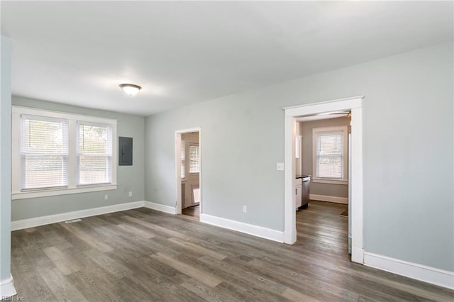 empty room with dark hardwood / wood-style flooring and electric panel