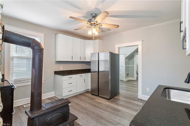 kitchen featuring ceiling fan, sink, light hardwood / wood-style flooring, stainless steel fridge, and white cabinets