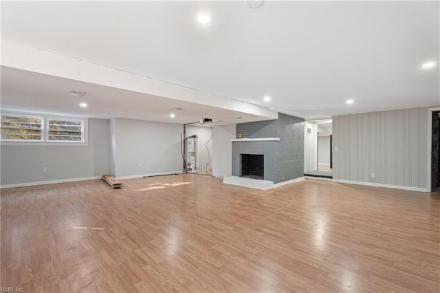 unfurnished living room with a brick fireplace, light hardwood / wood-style flooring, and water heater