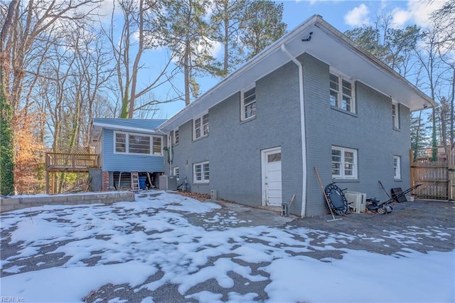 snow covered house featuring central air condition unit and a deck