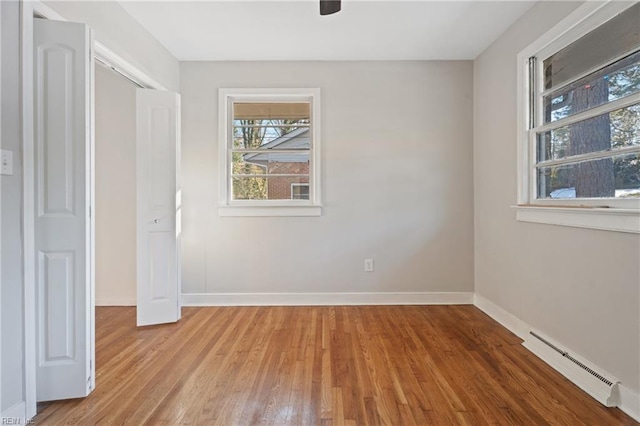 unfurnished bedroom featuring light wood-type flooring, a closet, ceiling fan, and a baseboard radiator